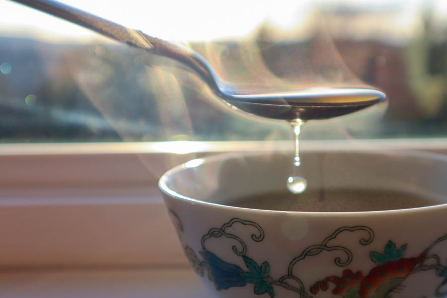 A drop of oyster mushroom broth falling from a spoon